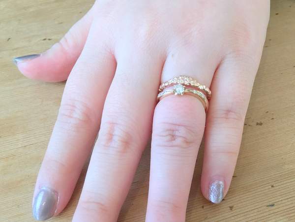 ピンクゴールドの婚約指輪と結婚指輪を重ねづけした女性の手