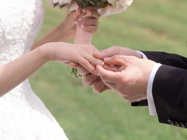 女性の右手薬指に結婚指輪をはめようとしている男性