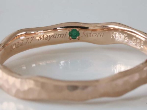ピンクゴールドの指輪内側にエメラルドと刻印が入った結婚指輪