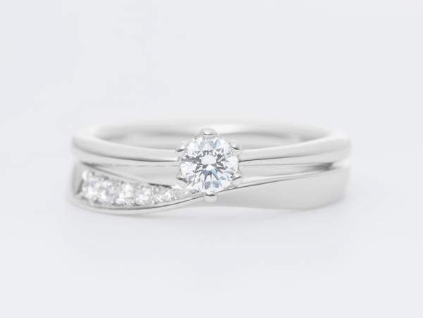 プラチナの一粒ダイヤの婚約指輪と中央がねじられたデザインの結婚指輪