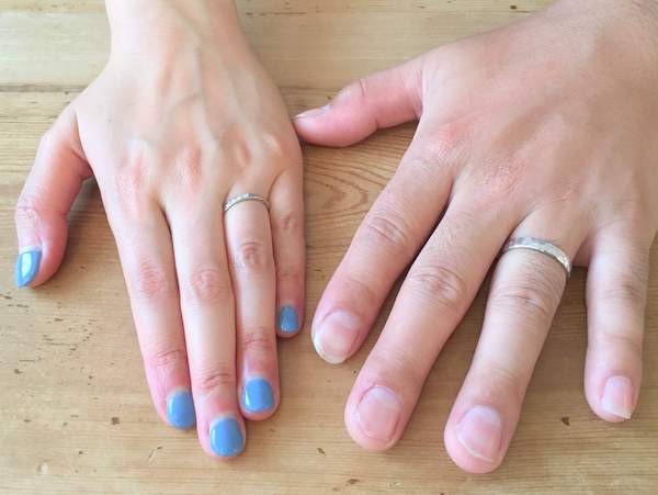 プラチナの平打ち結婚指輪を嵌めた男女の手