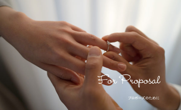 男性が女性の指に婚約指輪をはめ、プロポーズしている画像